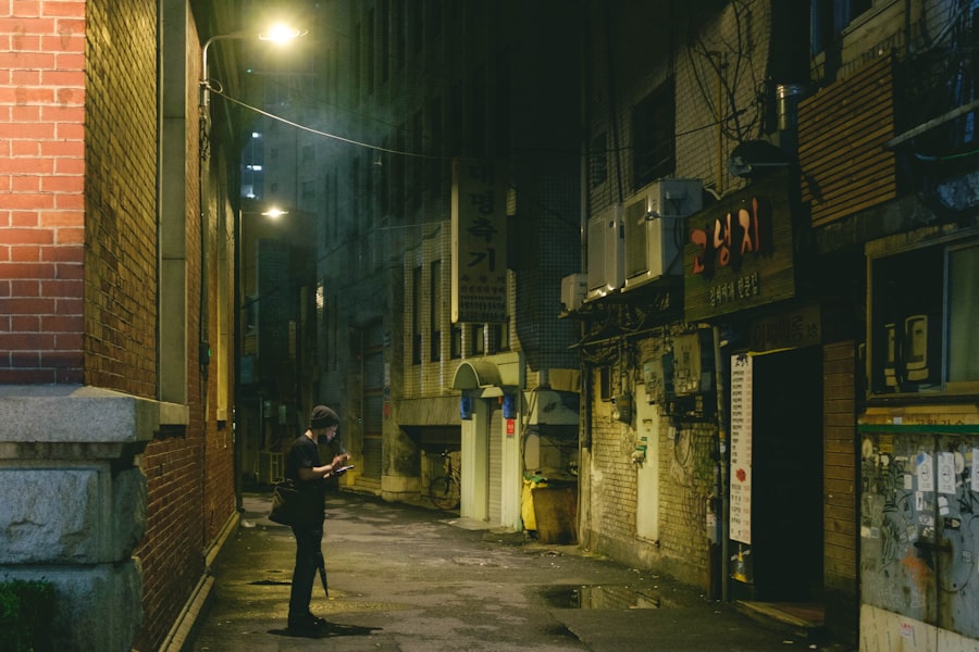 Pessoa usando o celular em um beco noturno de Seoul
